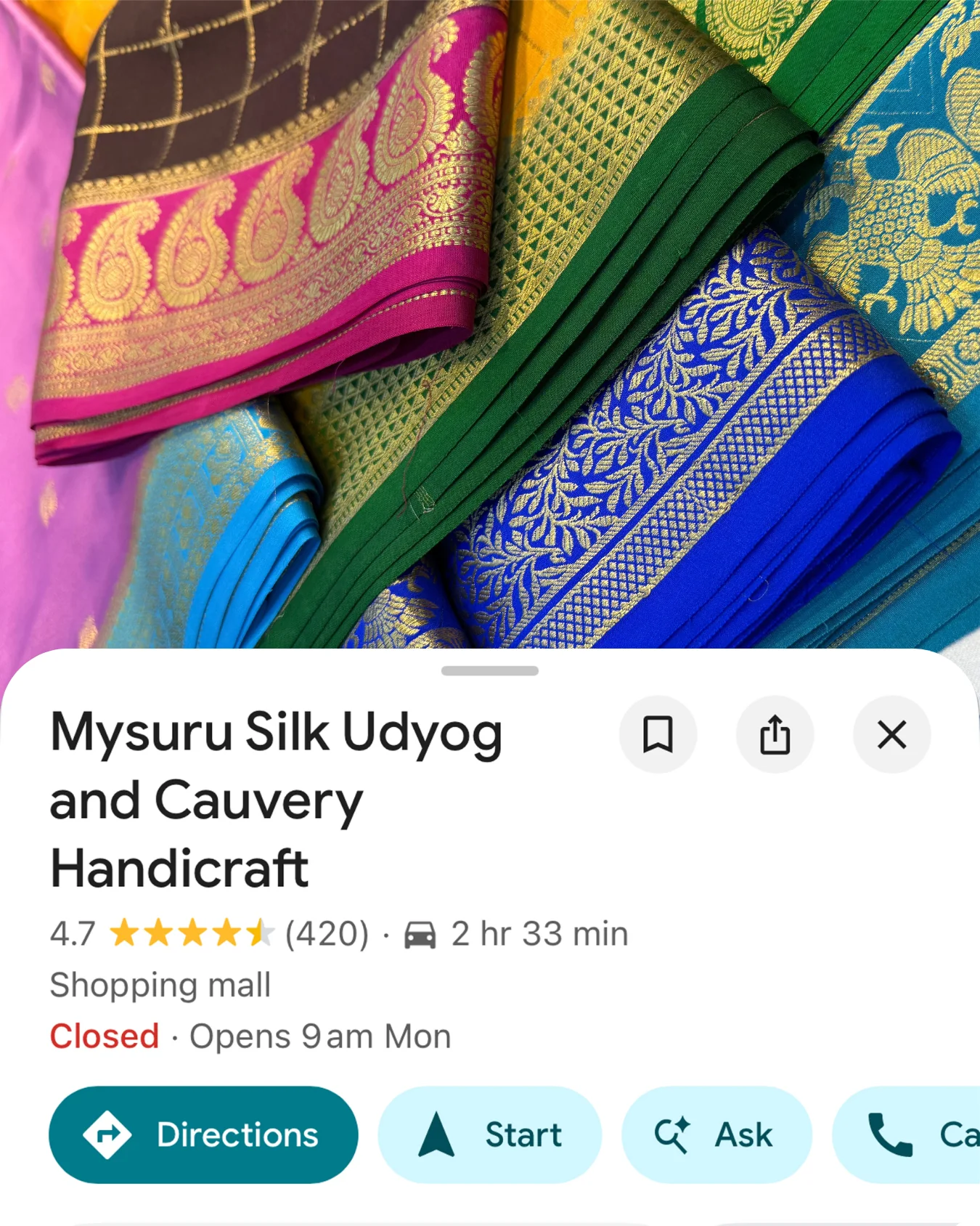 Card for Mysuru Silk Udyog and Cauvery Handicrafts — silk sarees folded in stacks.
